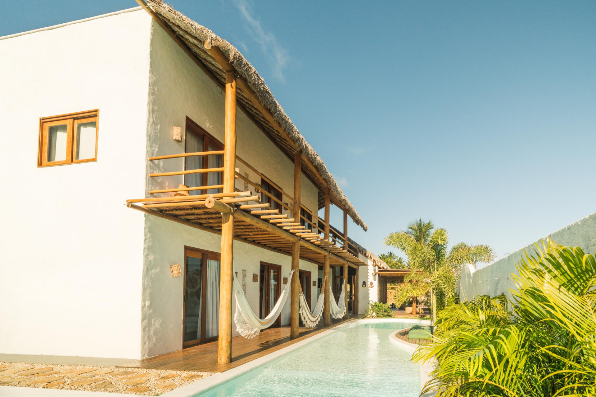 Fachada branca da Azulli com varandas de madeira, redes e piscina